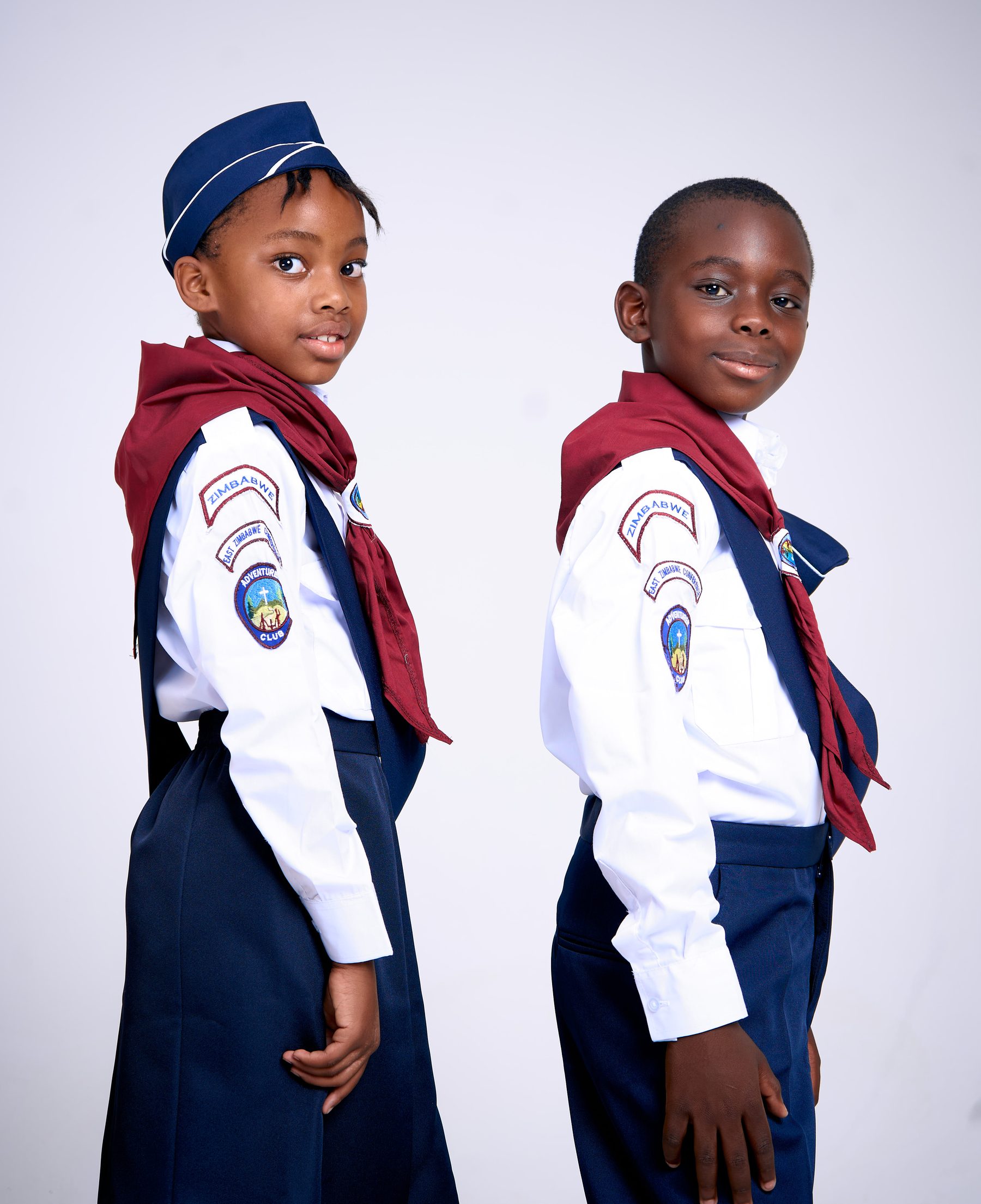 Two children wearing Adventurer Club uniforms with maroon sashes and embroidered patches